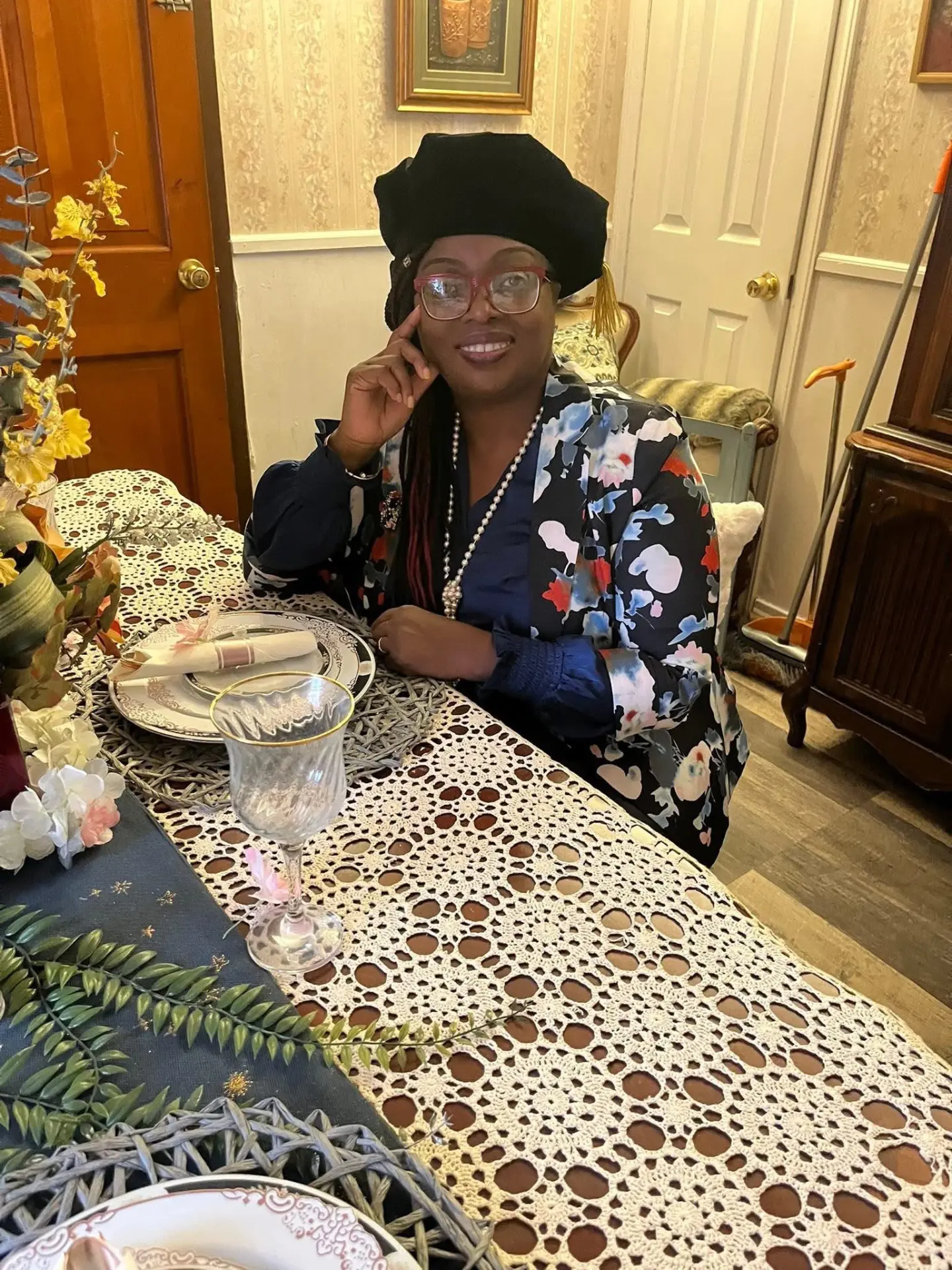 Dr. Clariona Griffith seated at an elegantly set table, wearing a doctoral tam